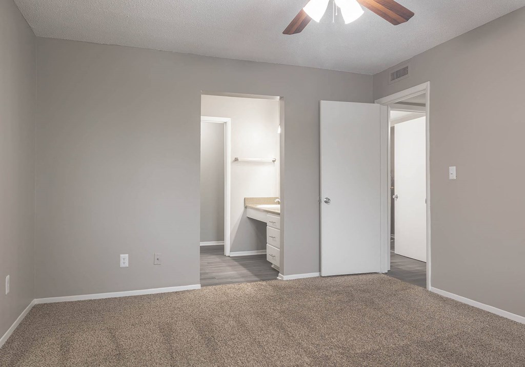 a bedroom with a desk and a ceiling fan
