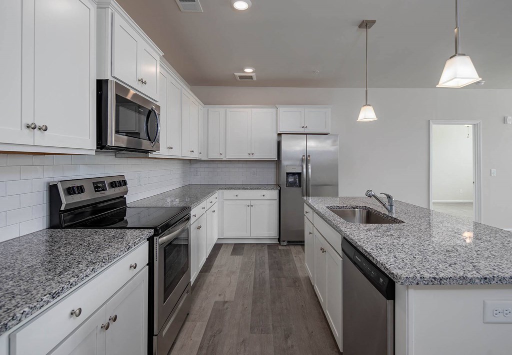 a kitchen with white cabinets and gray countertops