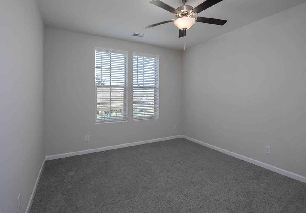 a bedroom with gray walls and a ceiling fan