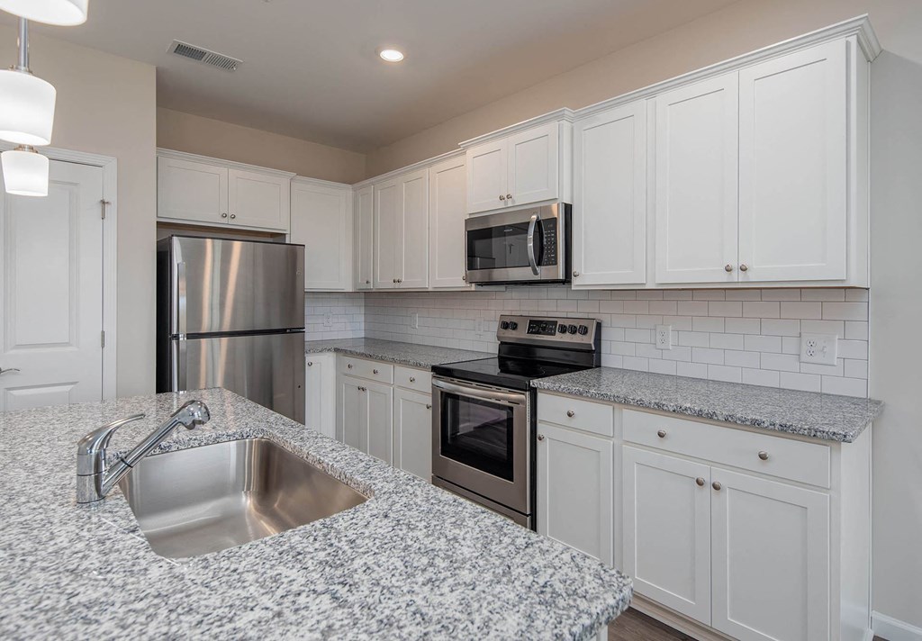 a kitchen with white cabinets and granite countertops