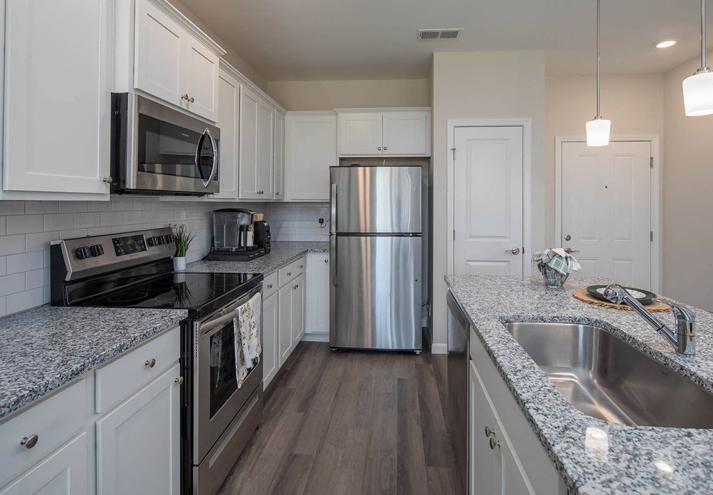 a kitchen with white cabinets and gray countertops
