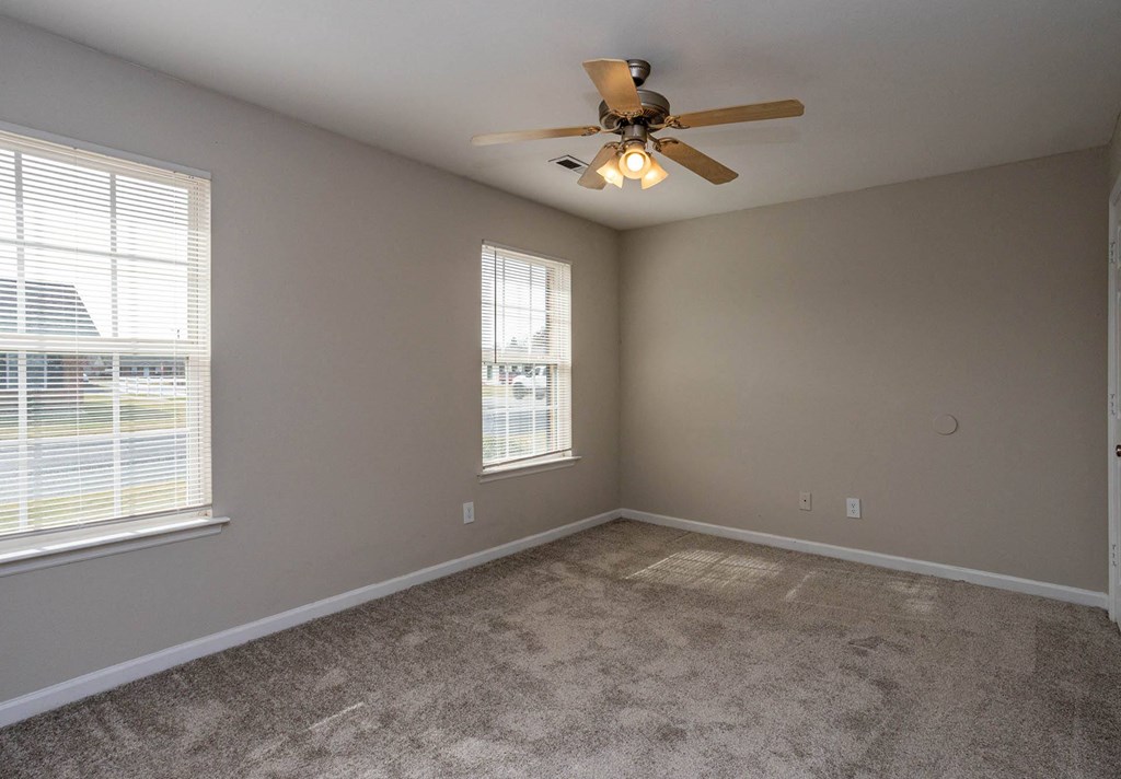 a bedroom with two windows and a ceiling fan