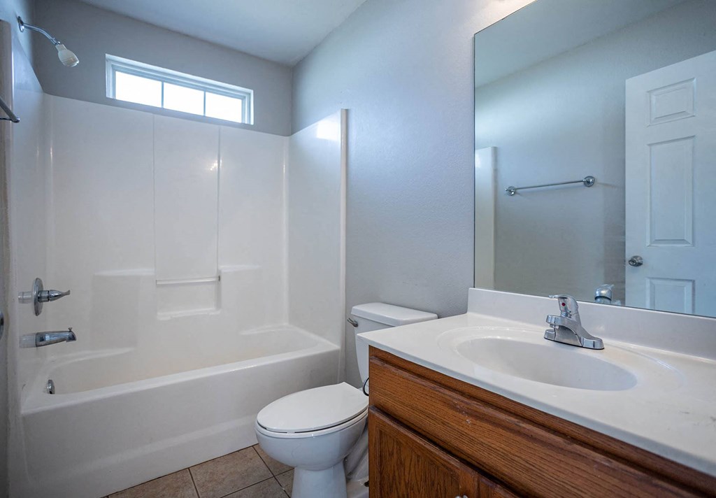 a bathroom with a white toilet next to a white bathtub
