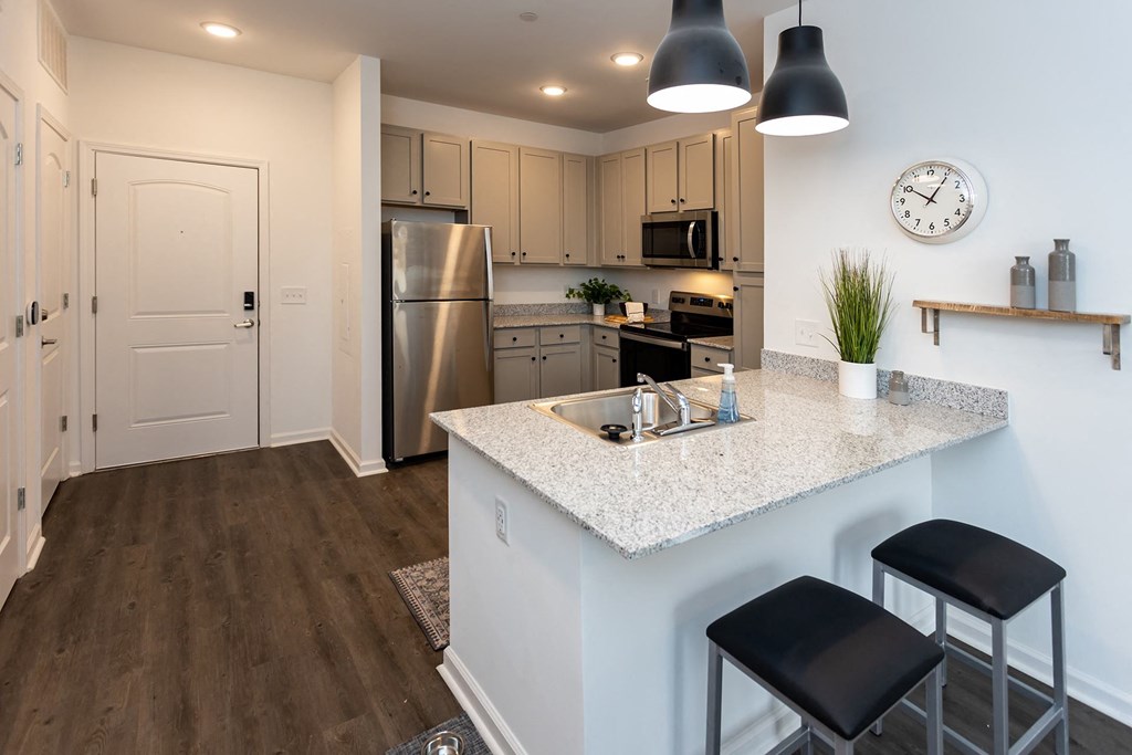 A kitchen with a white countertop and black bar stools.