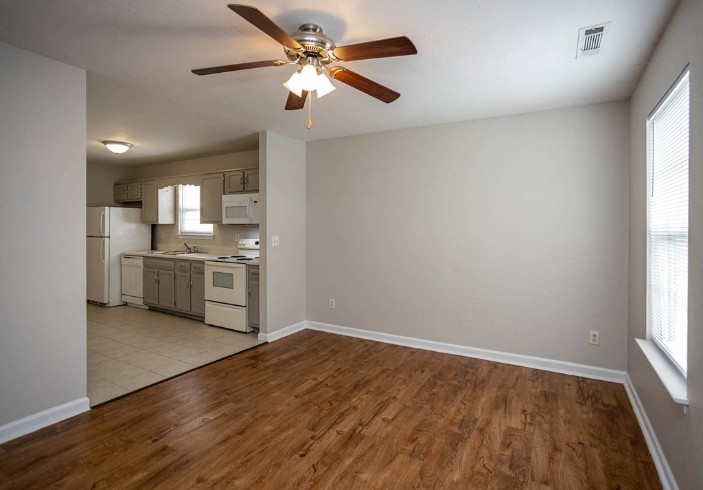 a bedroom with a ceiling fan and a kitchen in the background