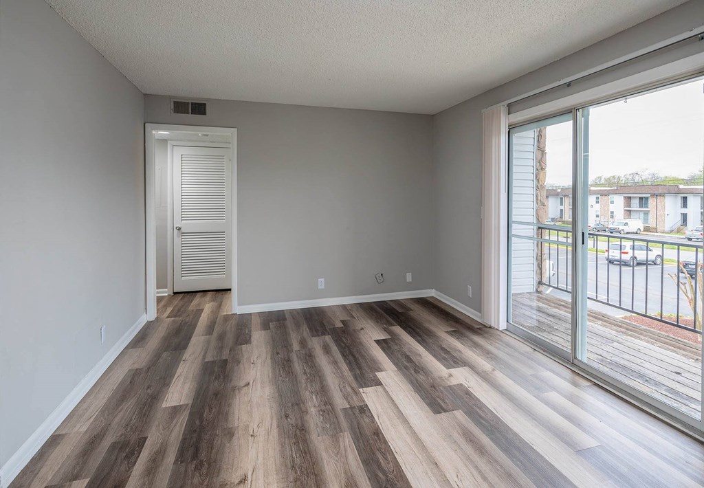 a bedroom with hardwood flooring and a sliding glass door leading to a balcony