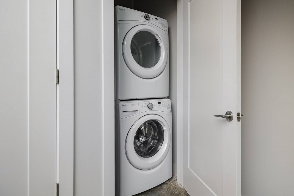 A white washing machine is in a small white closet.