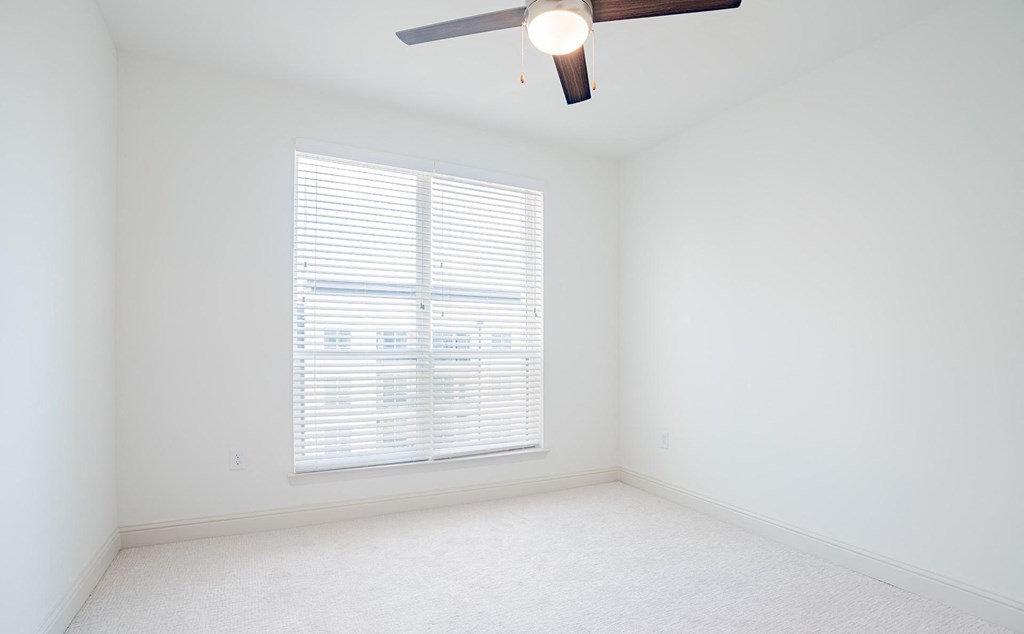 an empty room with a large window and a ceiling fan