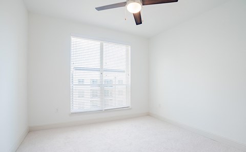 an empty room with a large window and a ceiling fan