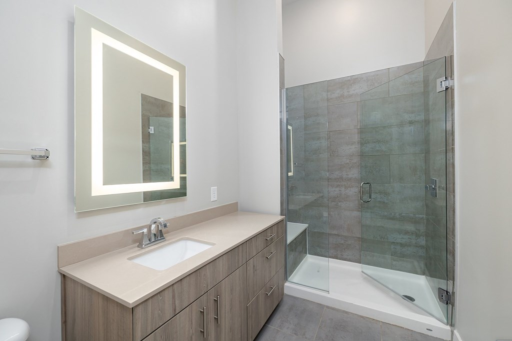 A bathroom with a sink, mirror, and walk-in shower.