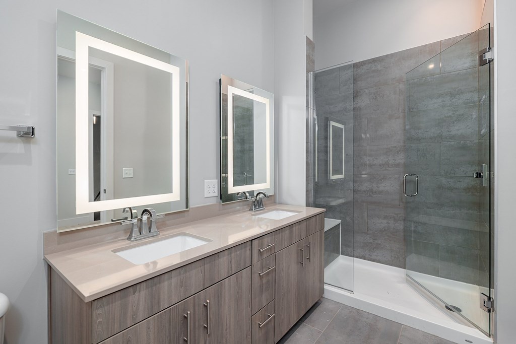 A modern bathroom with a sink, mirrors, and a walk-in shower.