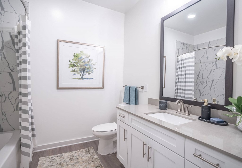 a white bathroom with a large mirror and a toilet
