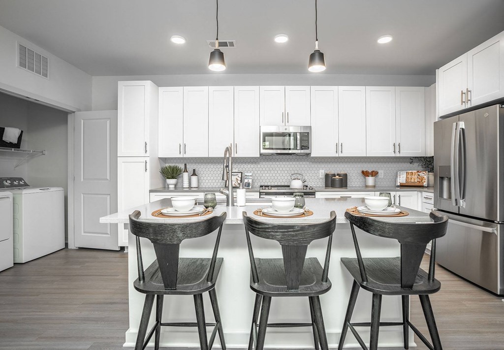 kitchen with island and stools in front of a counter with 3 stools