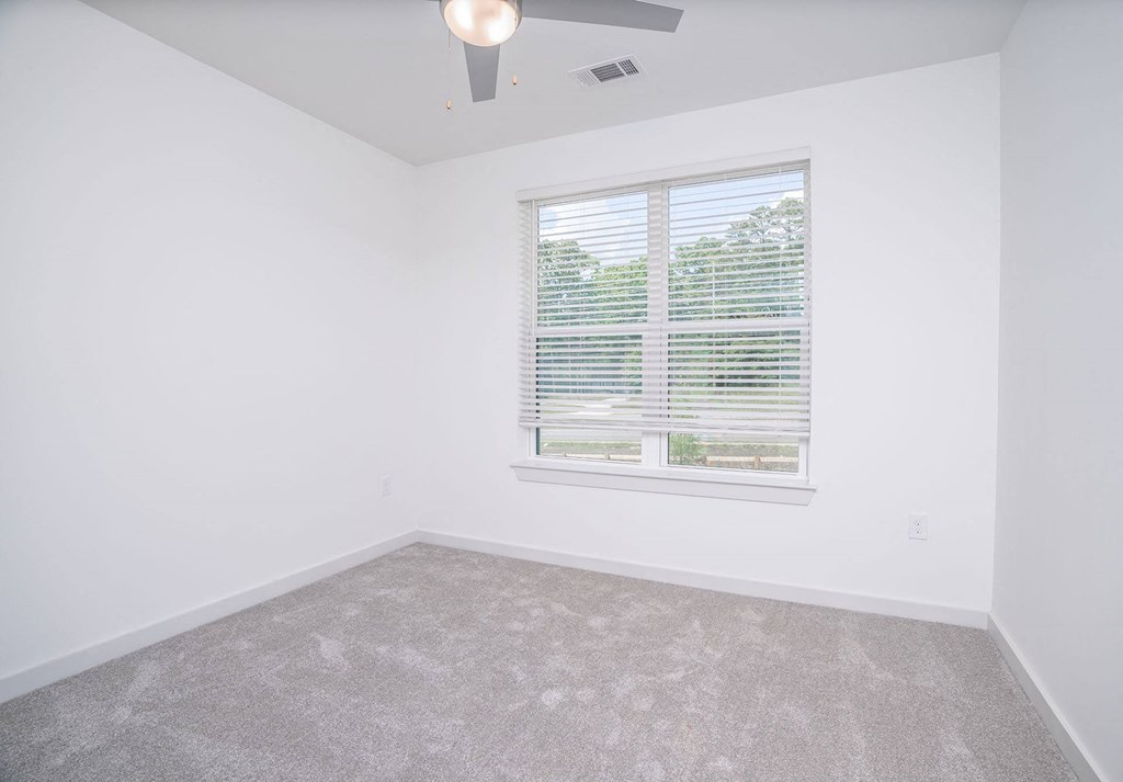 an empty room with a window and a ceiling fan