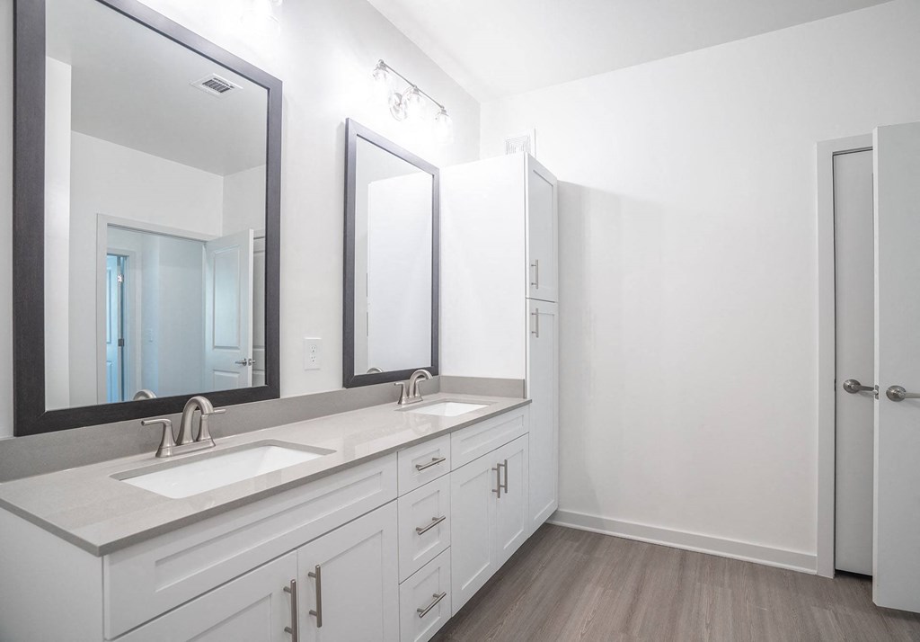 a white bathroom with two sinks and three mirrors