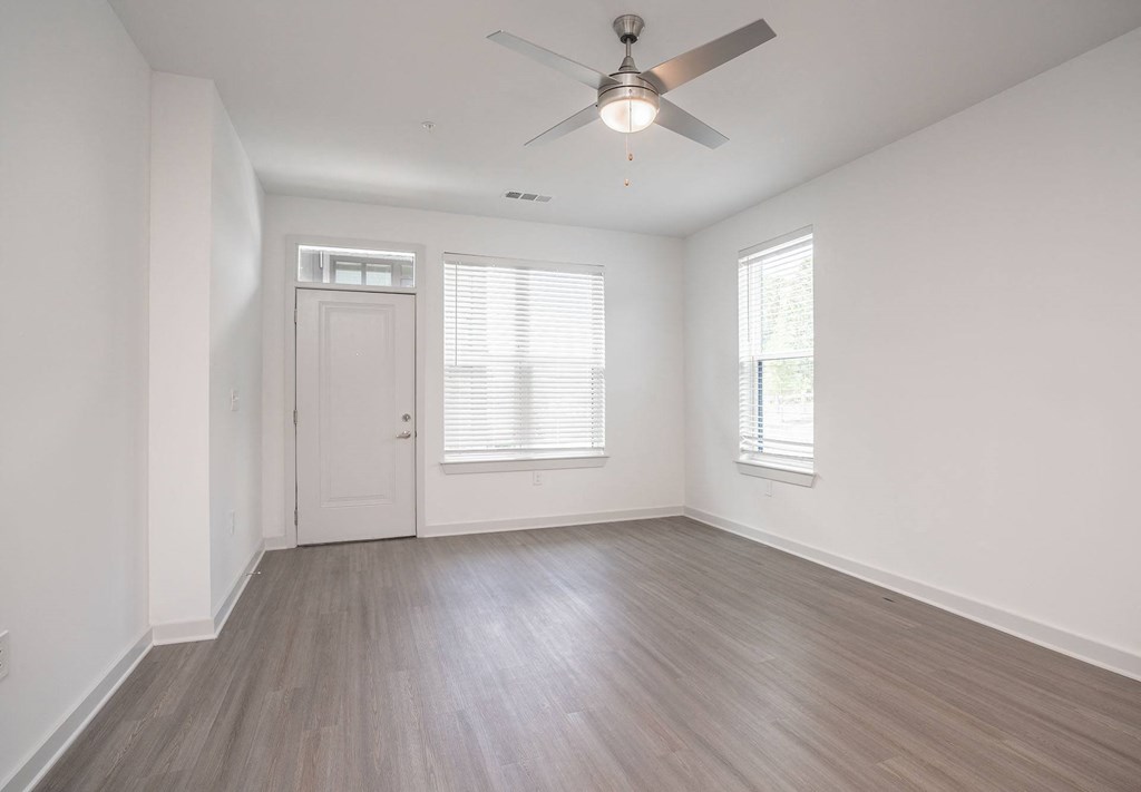an empty living room with white walls and a ceiling fan