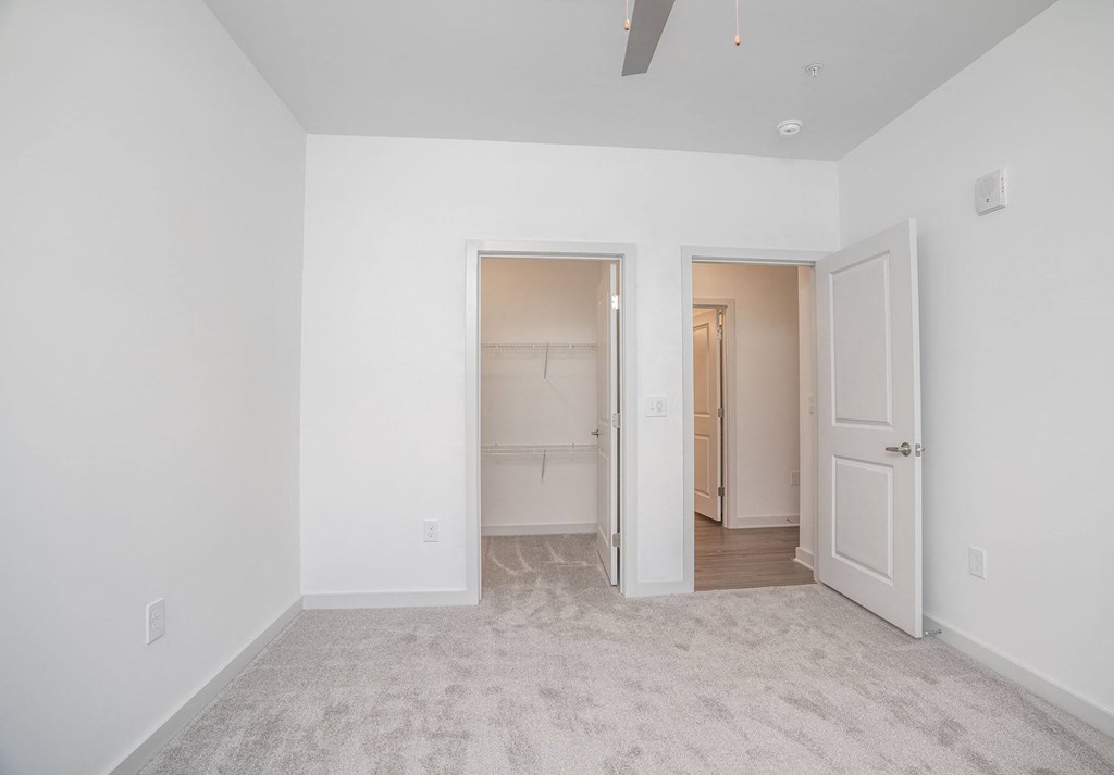 a bedroom with white walls and a door to a closet