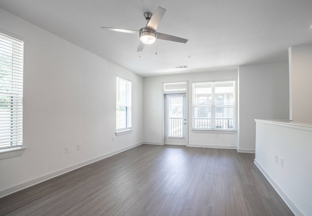 an empty living room with white walls and a ceiling fan