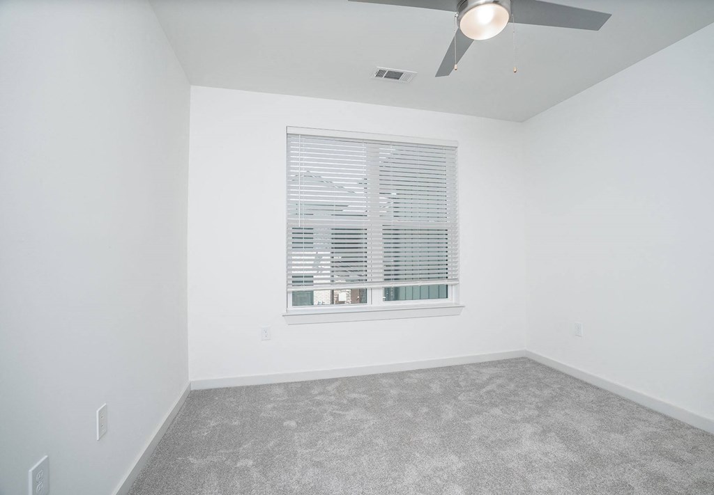 an empty room with a window and a ceiling fan