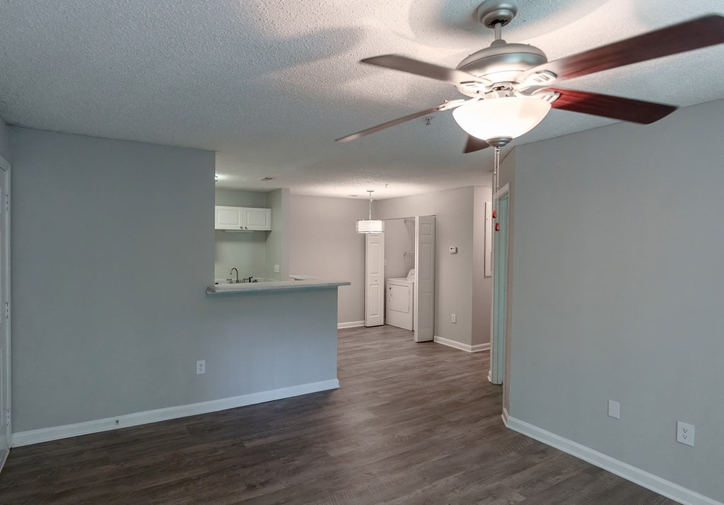 an empty living room and kitchen with a ceiling fan