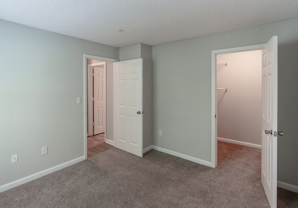 an empty bedroom with a closet and a door to a bathroom