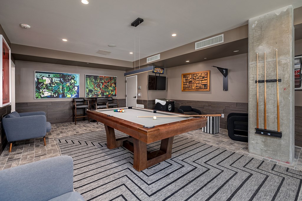 A billiard table is in the middle of a room with a grey carpet.