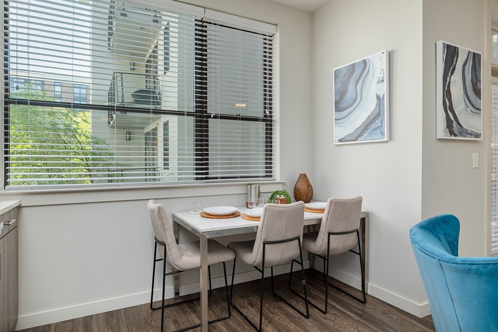 A dining room with a table set for two and a view of a building outside the window.