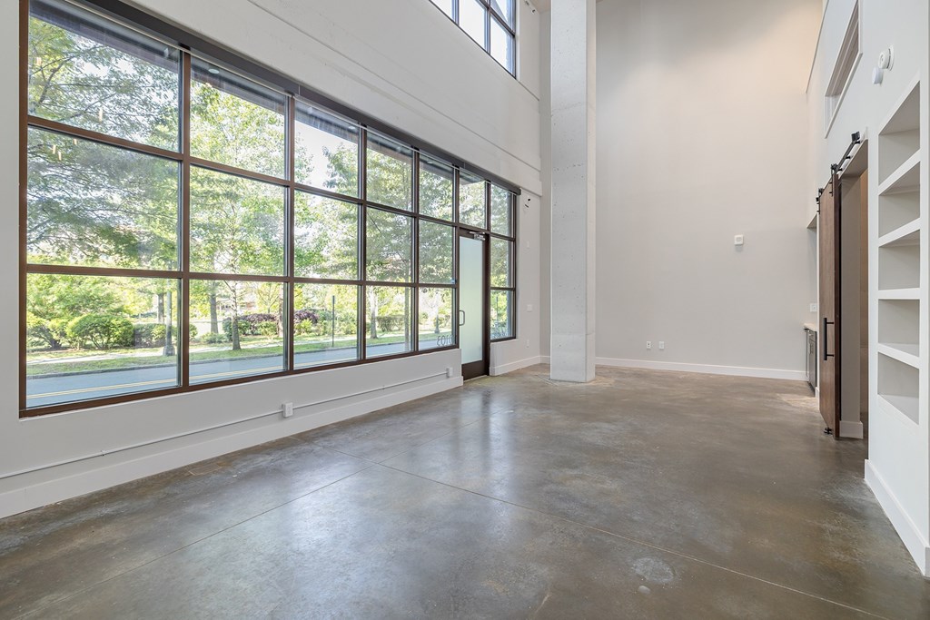 A large empty room with a view of trees outside the window.