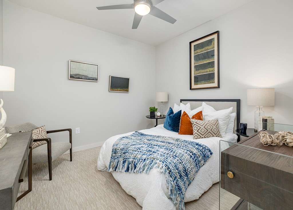 A bedroom with a bed, a ceiling fan, and a nightstand.