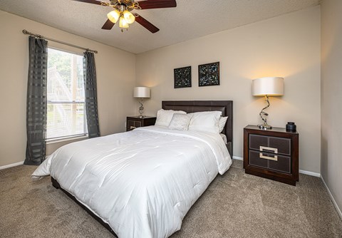A bedroom with a large bed and a ceiling fan.
