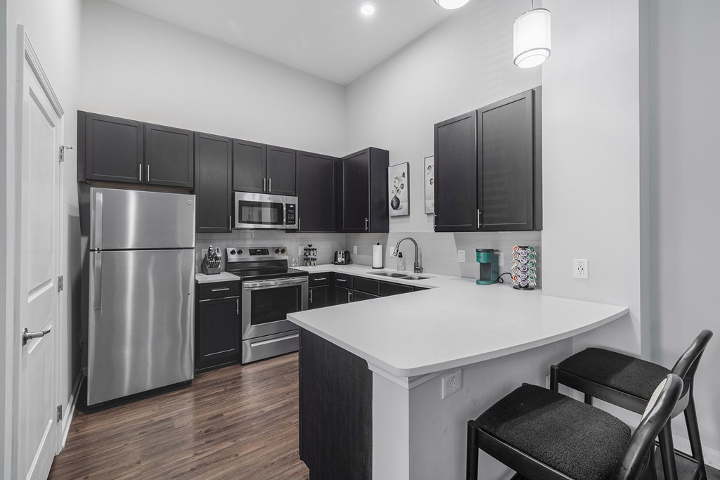 A kitchen with a white island and black cabinets.