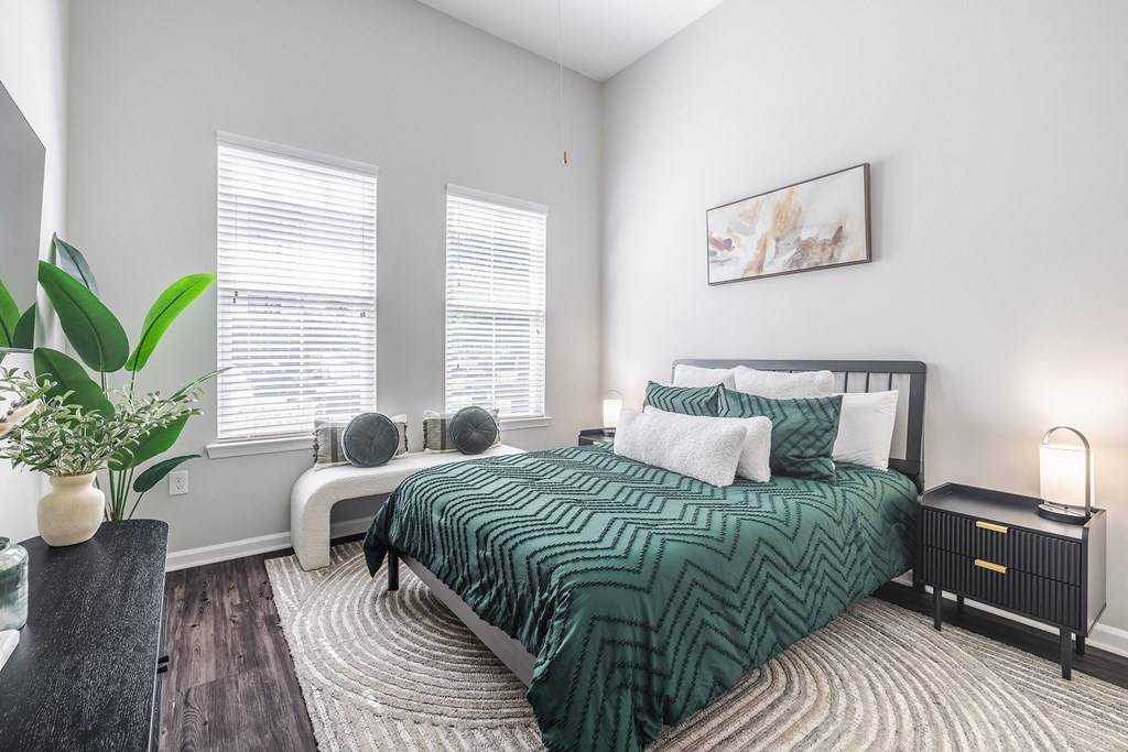 A bedroom with a large bed and a potted plant.