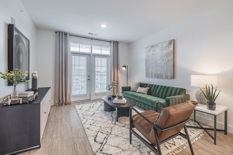 A living room with a green couch and a brown leather chair.