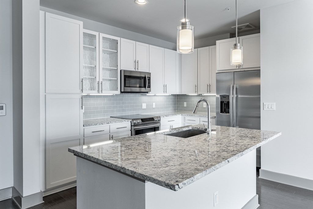 A modern kitchen with granite countertops and stainless steel appliances.
