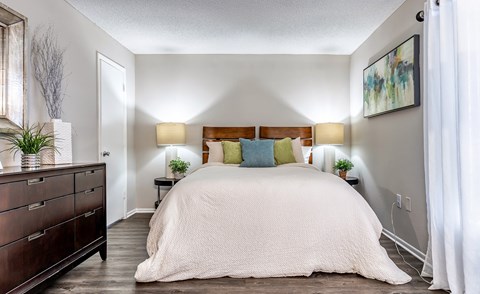 A bedroom with a large bed and a wooden dresser.