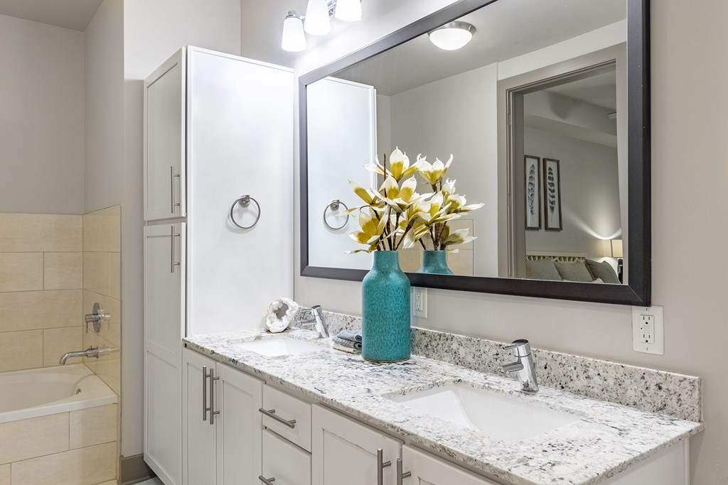 A bathroom with a white vanity and a blue vase with flowers.