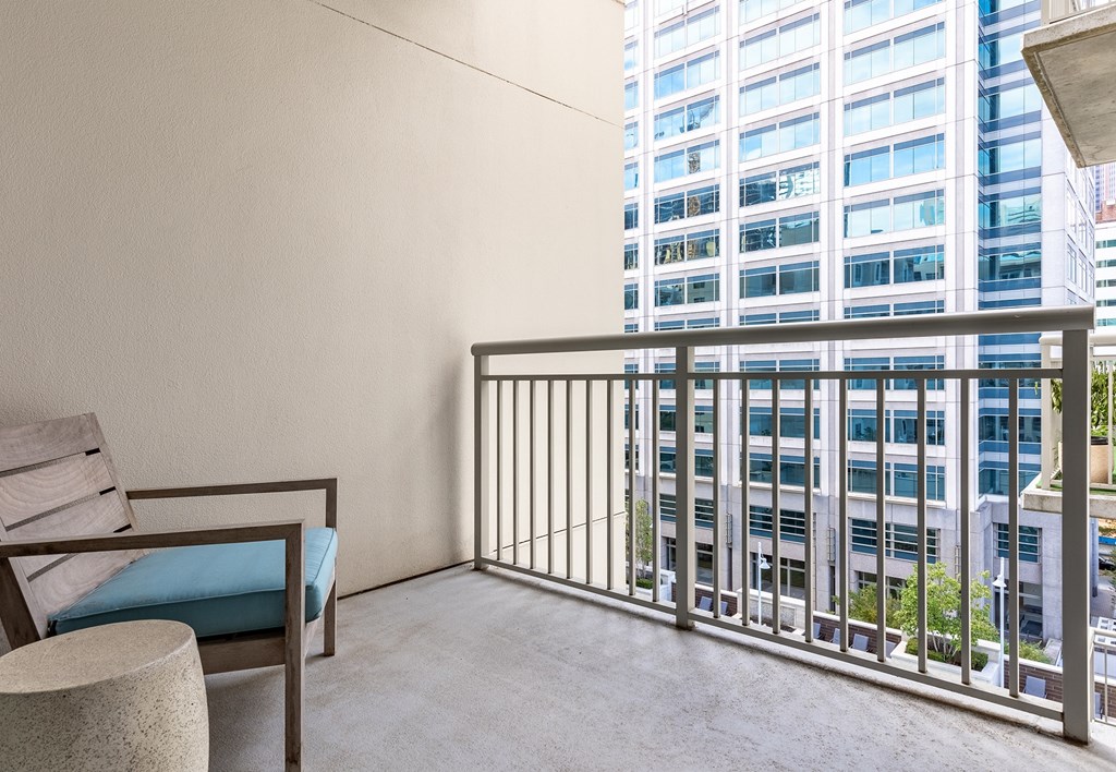 A balcony with a chair and a table with a blue cushion.