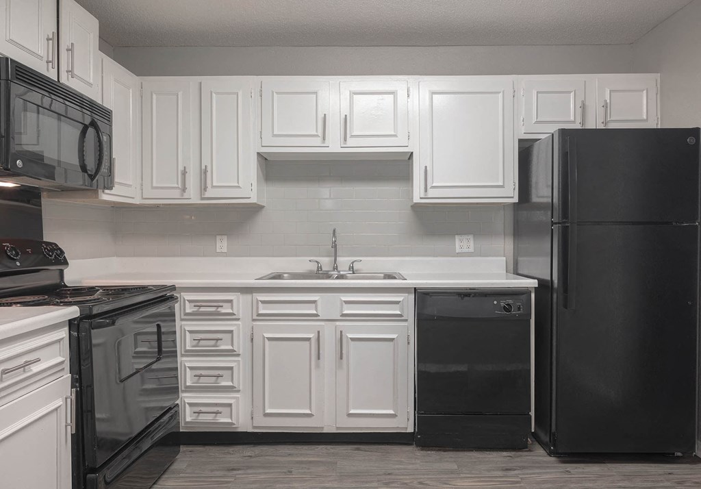 a kitchen with white cabinets and black appliances