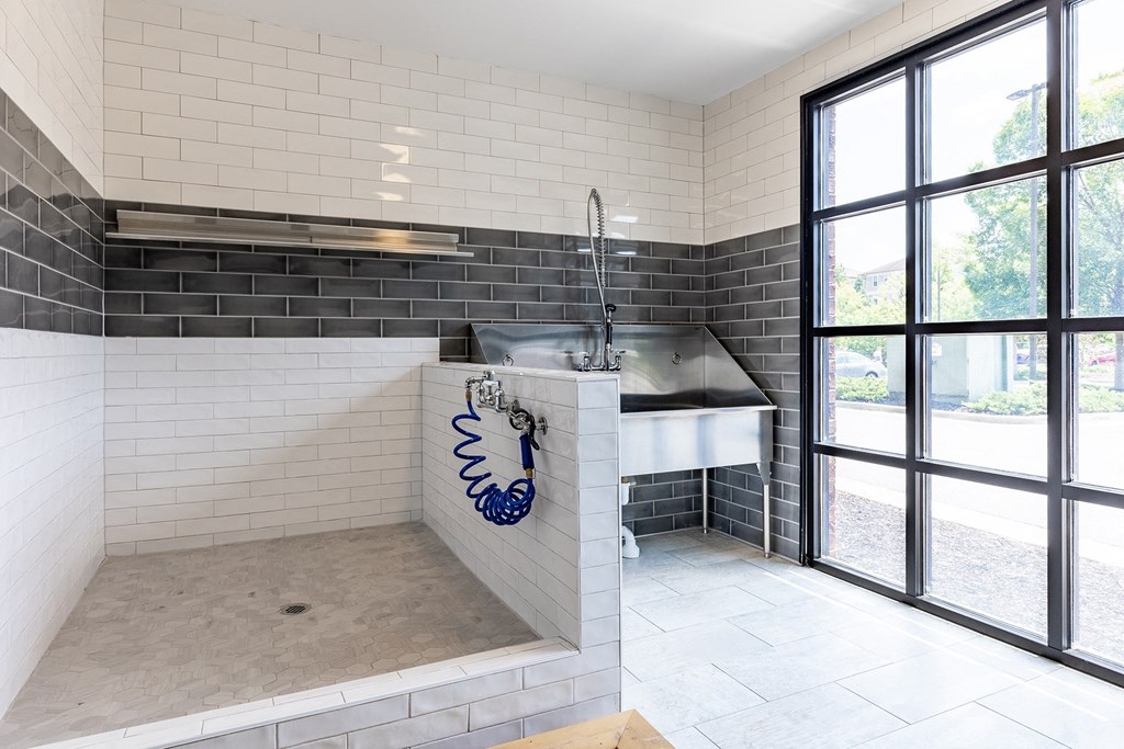 a large white tiled bathroom with a sink and a window