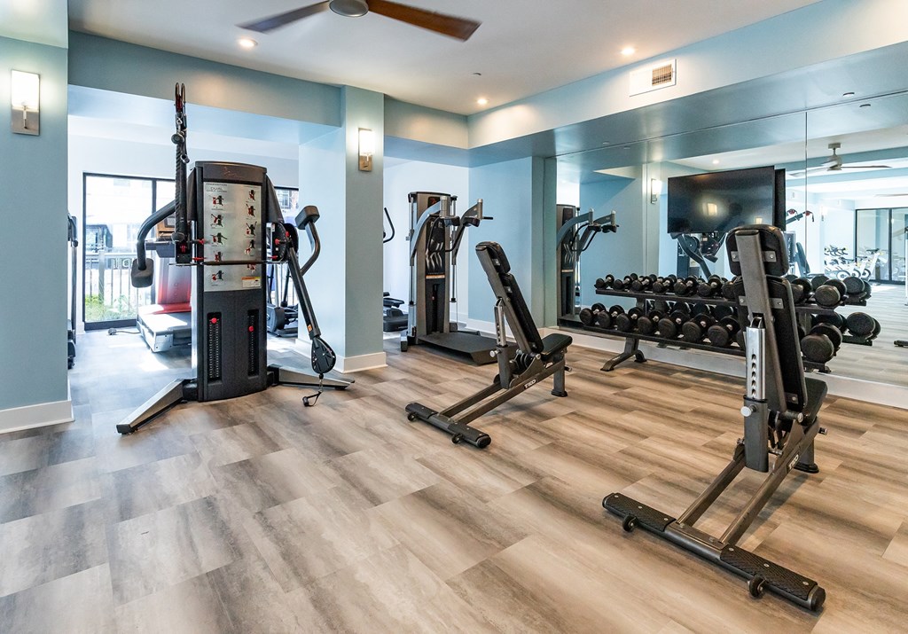 a gym with exercise machines and weights on a wooden floor