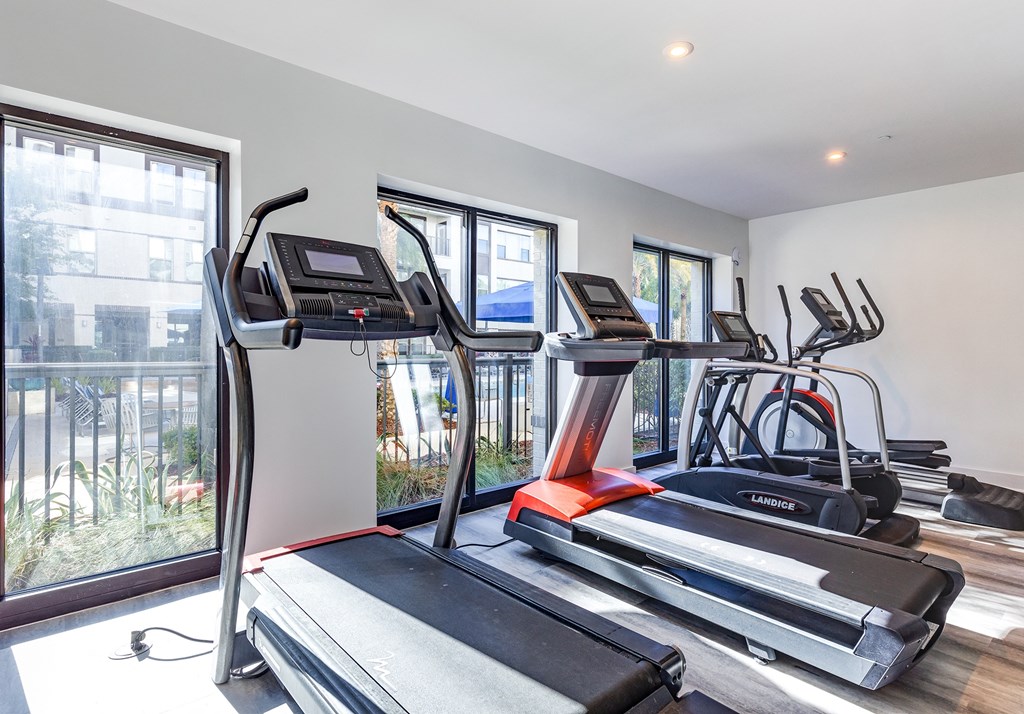 two treadmills and other exercise equipment in an apartment gym