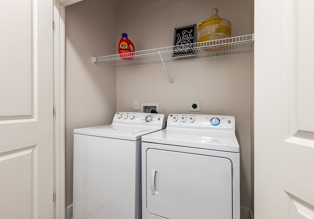 a washer and dryer in a small laundry room with a shelf above them