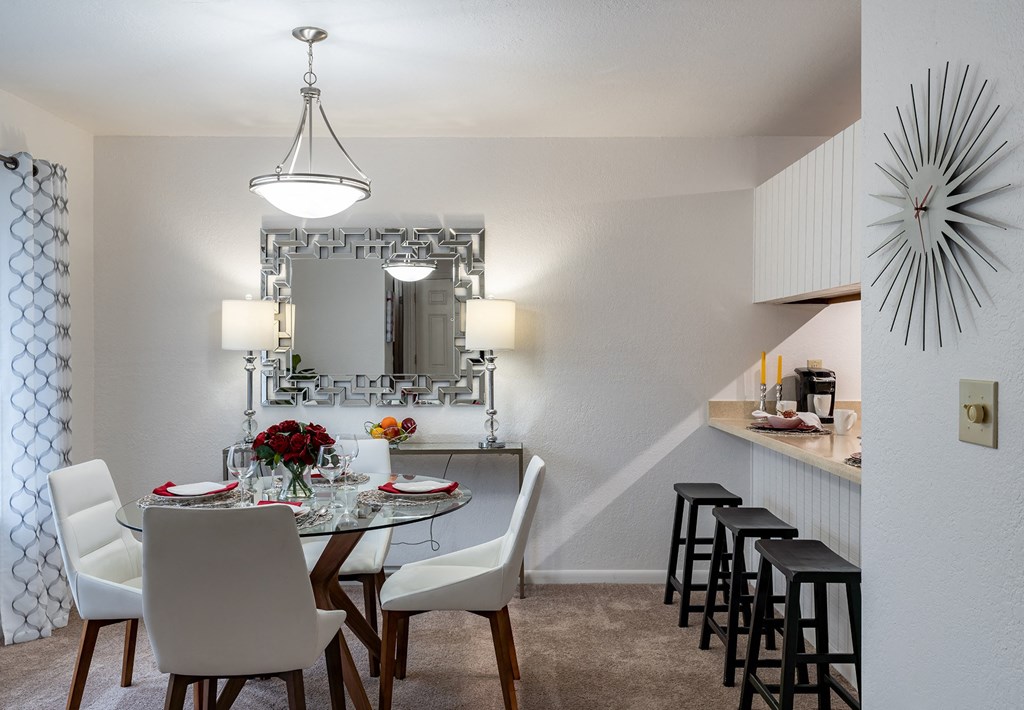 a dining area with a glass table and white chairs  at Pheasant Run, Saginaw, Michigan