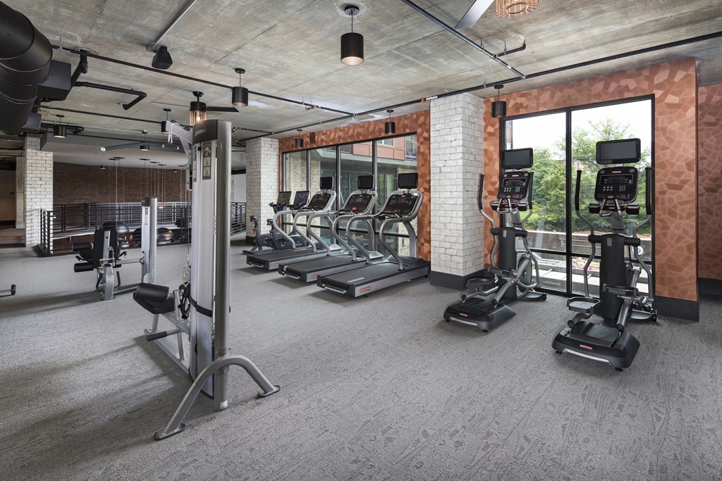 a gym with treadmills and other exercise equipment in a room with glass windows