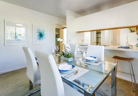 a dining area with a glass table and white chairs