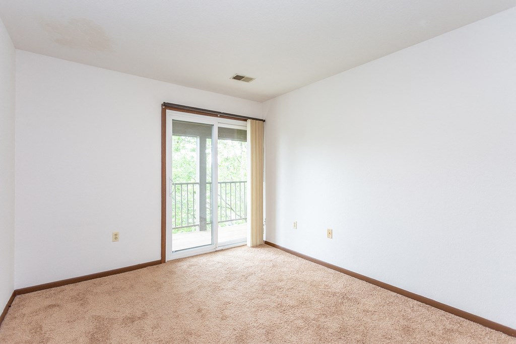 a bedroom with white walls and a sliding glass door