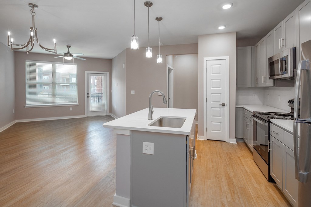 an open kitchen and living room with an island and a sink
