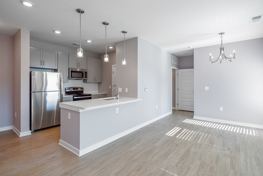 an empty kitchen and living room with a stainless steel refrigerator