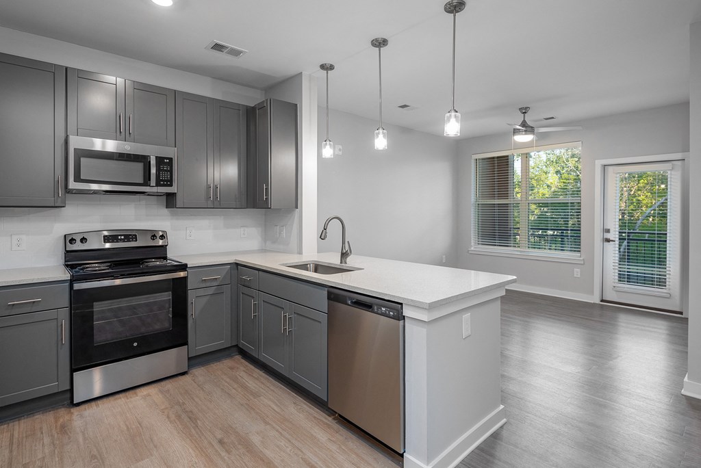 an empty kitchen with stainless steel appliances and a white counter top