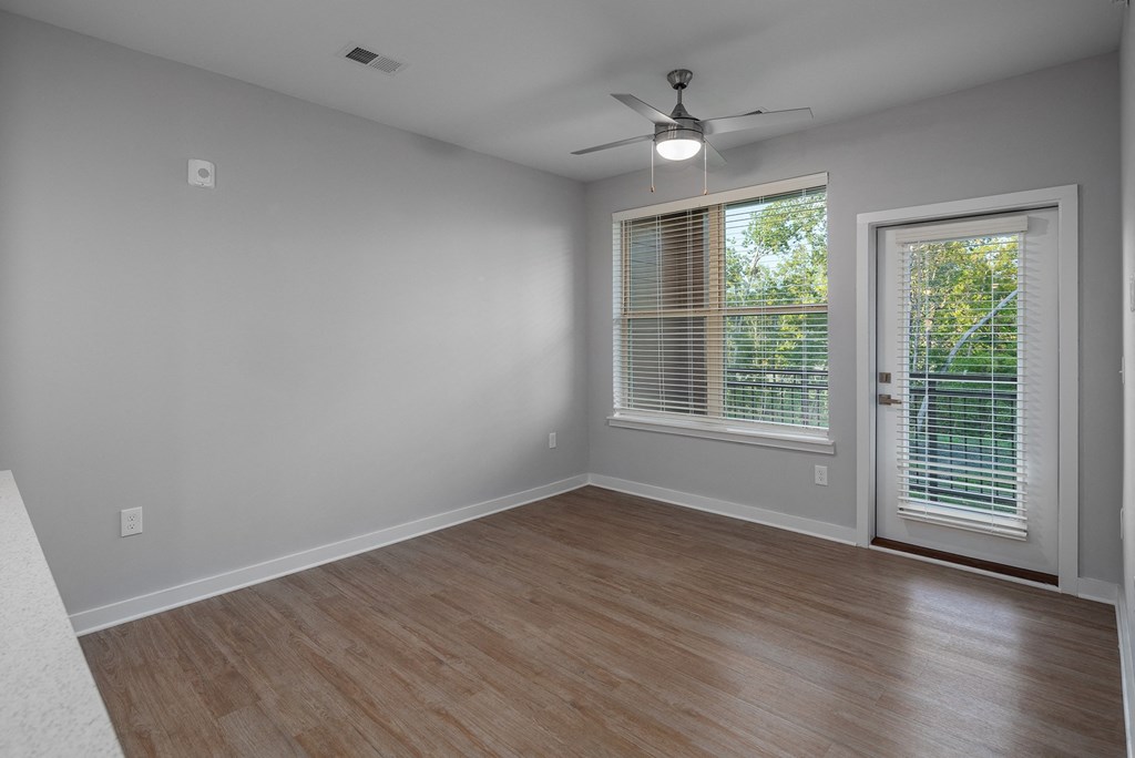 an empty living room with a window and a ceiling fan